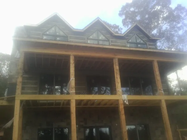 Dormers and porch framing on a large log home under construction — Roof Coating work by our crew in La Salle