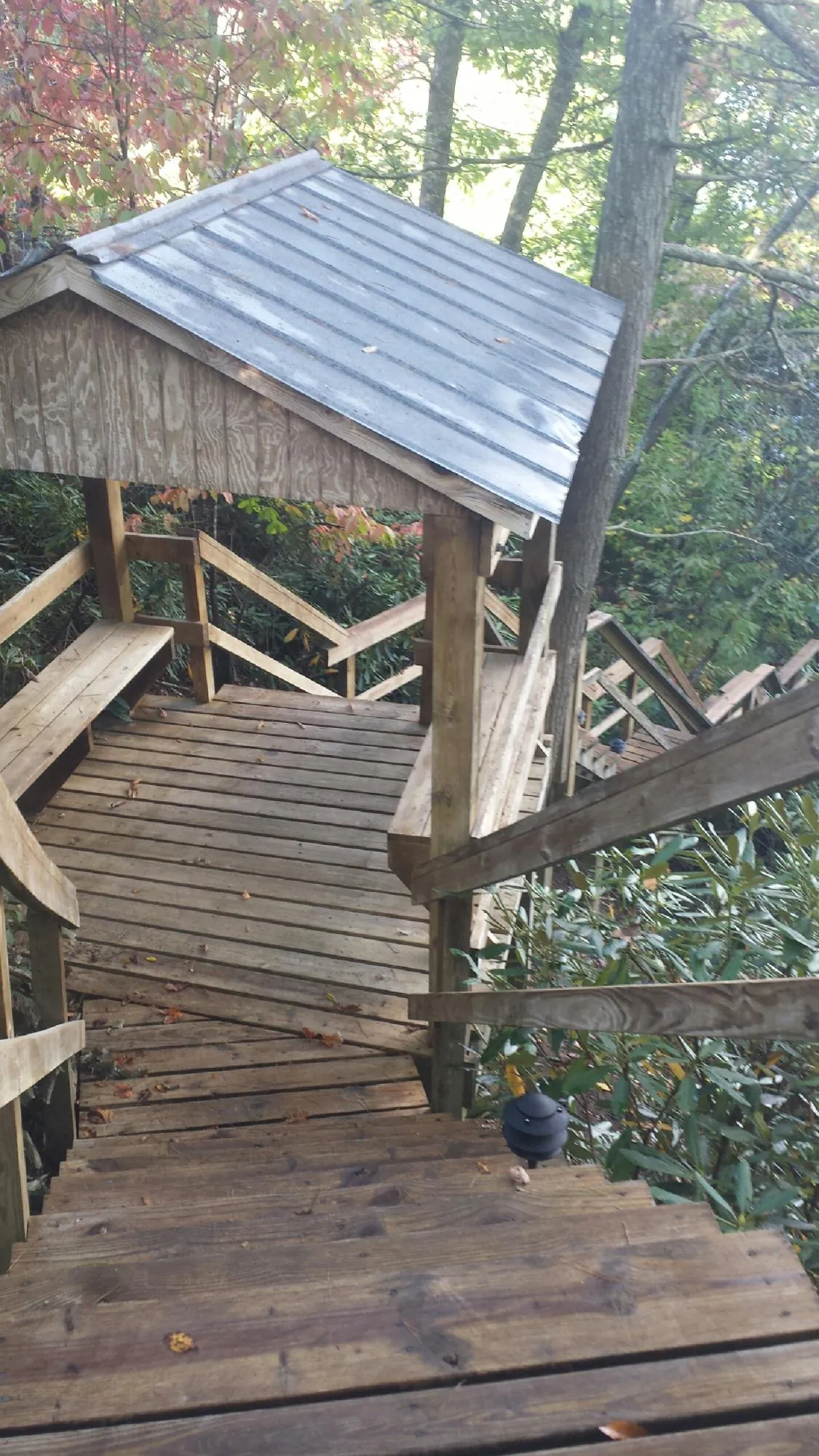Metal roofed shelter over wooden steps on a wooded walkway — Skylight Repair & Installation work by our crew in La Salle