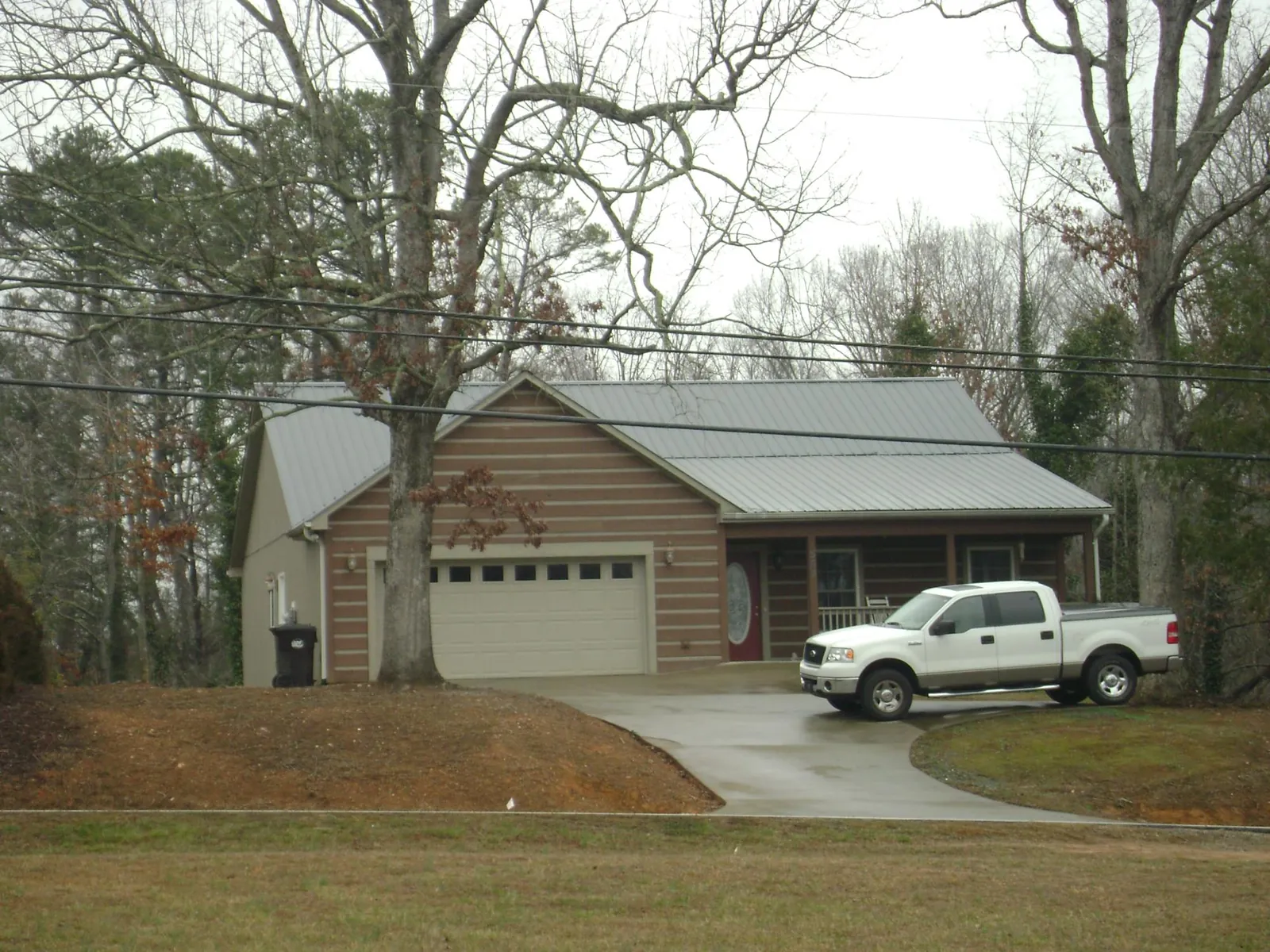 Gray metal roof on a log sided house with an attached two car garage in La Salle